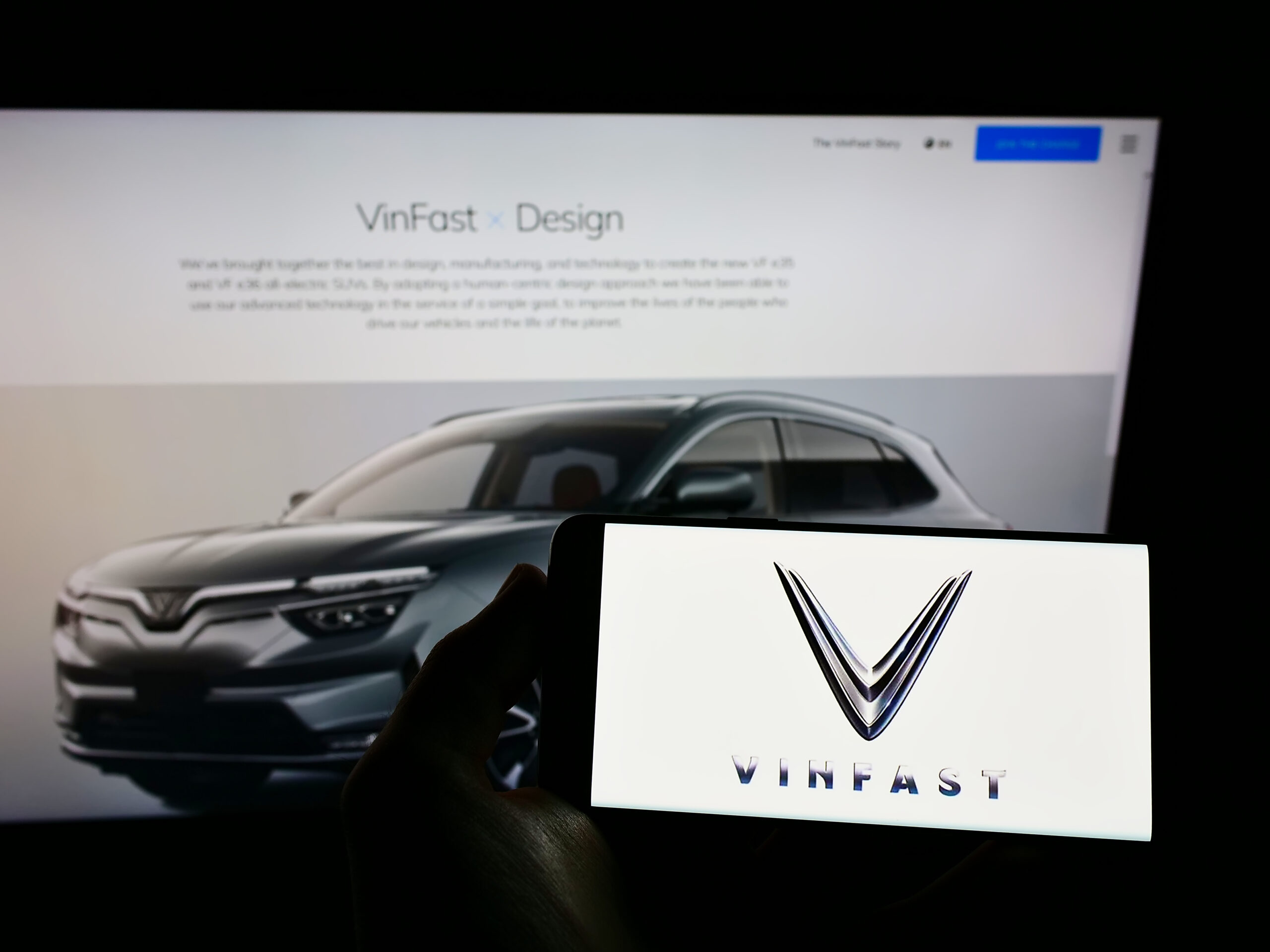 STUTTGART, GERMANY - Dec 05, 2021: Person holding cellphone with logo of car manufacturer VinFast on screen in front of webpage.